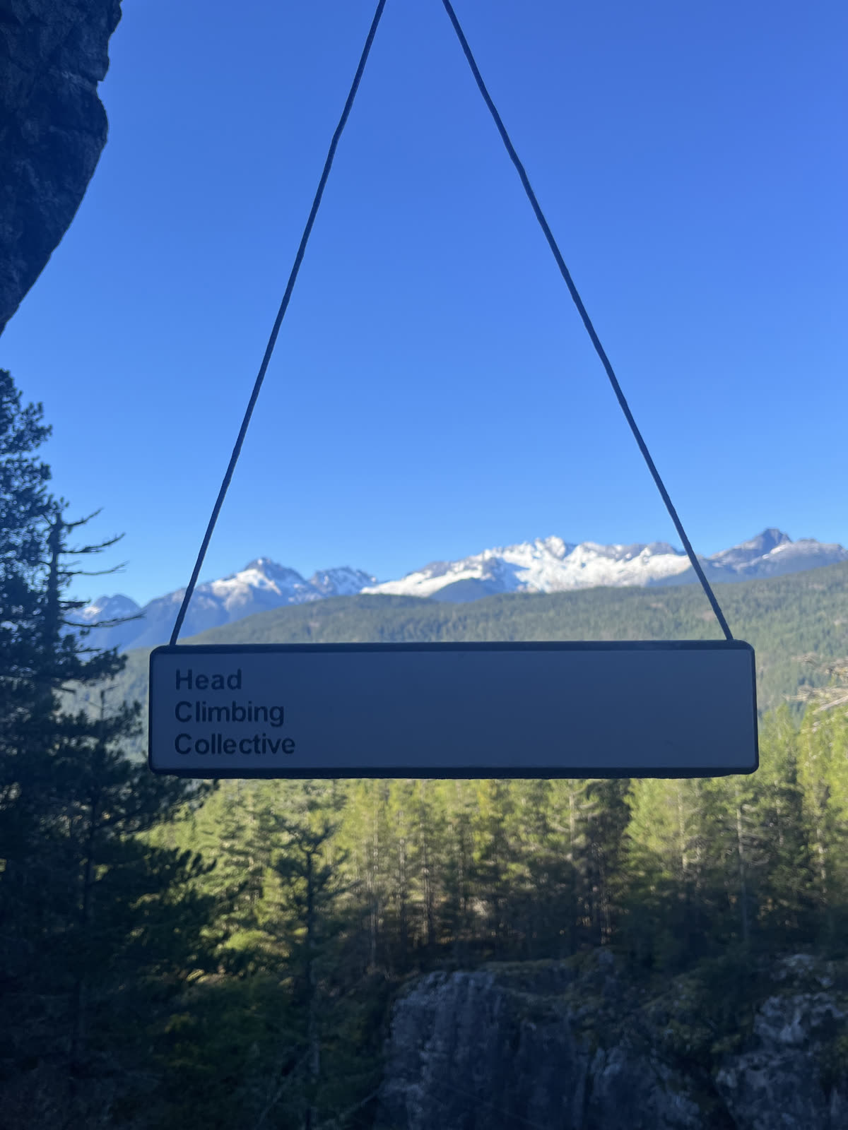 DriftBoard hanging from a cord against a blue sky with snow-capped Squamish mountains behind