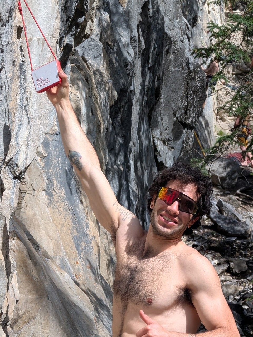 Smiling climber at the crag hanging from a TriEdge Crimp Block clipped to the wall